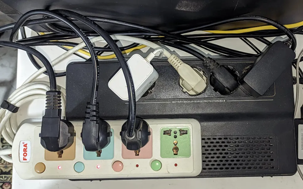 A UPS with several power cables and a power strip plugged into it