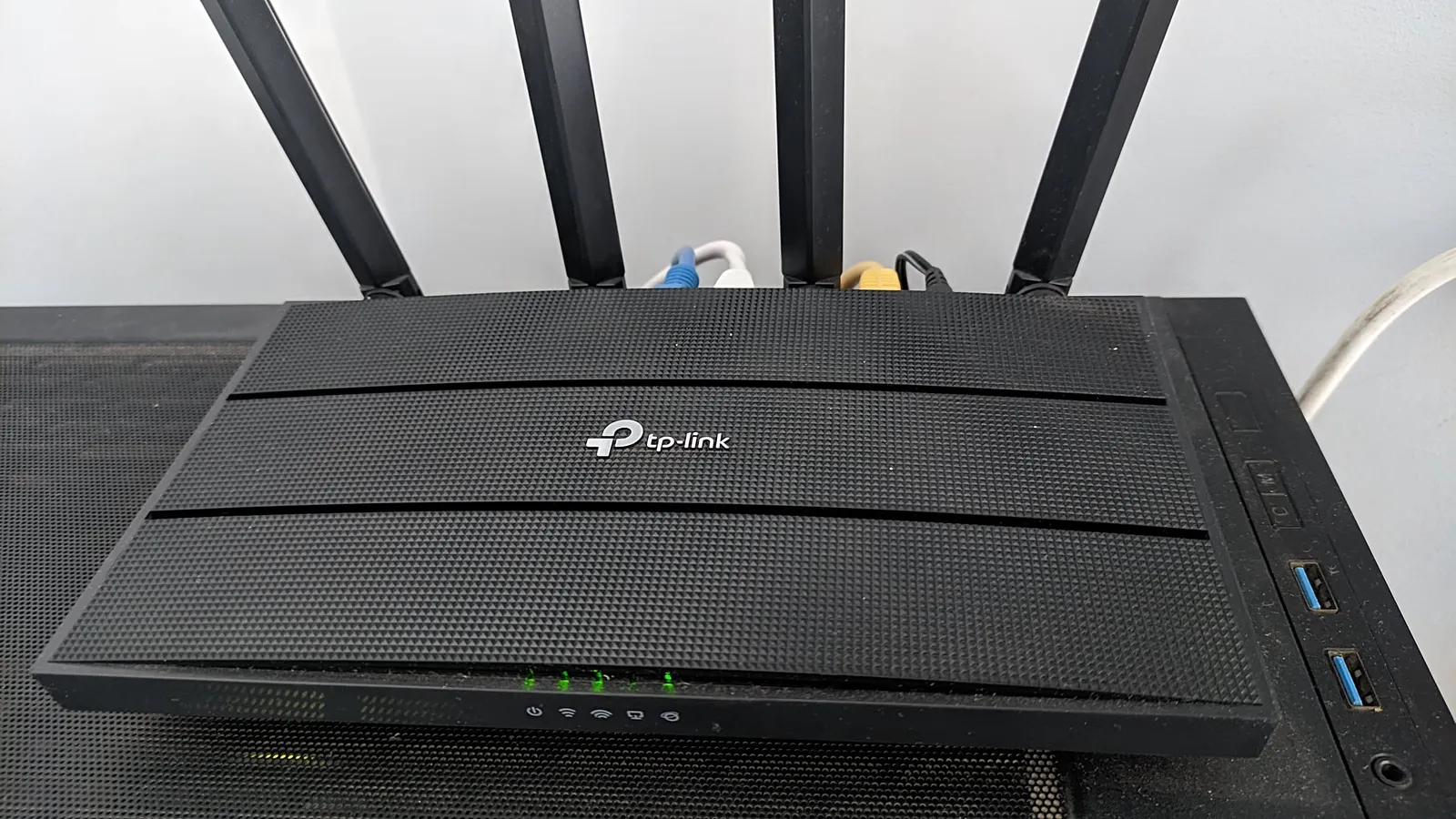 A TP-Link Wi-Fi router with four antennas, sitting on top of the desktop PC